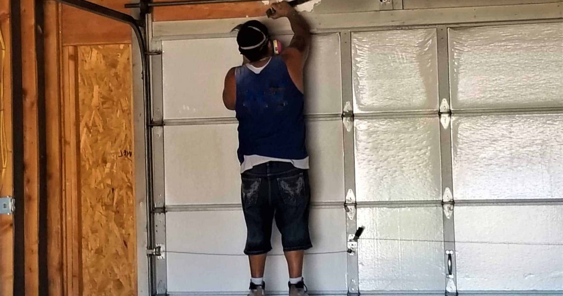 construction worker installing garage door spring