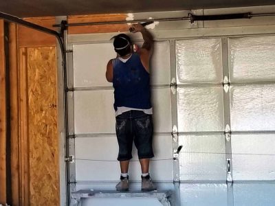 construction worker installing garage door spring